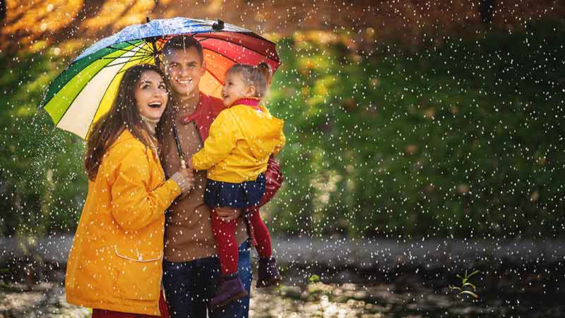 Parents with a child under a multicolored umbrella, representing the coverage of umbrella insurance.